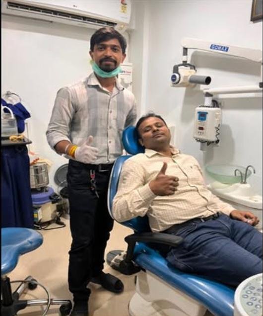 Patient post-treatment in dental chair giving thumbs up with Dr. Anshul Sahu